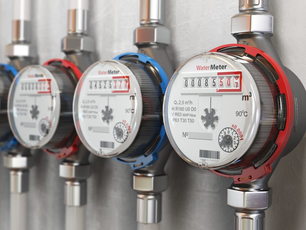 Row of water meters of cold and hot water on the wall background